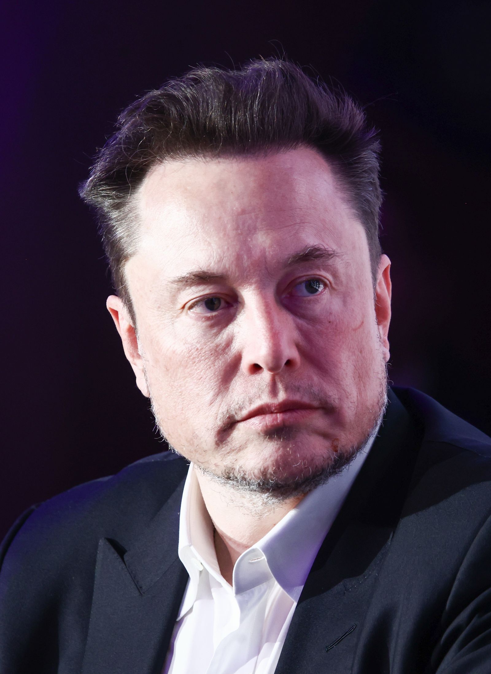 Image may contain Elon Musk Face Head Person Photography Portrait Adult Clothing Formal Wear Suit and Crew Cut