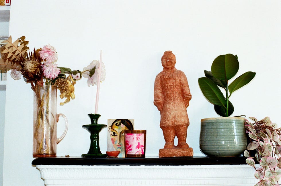 decorative mantel display featuring flowers plants and a statue