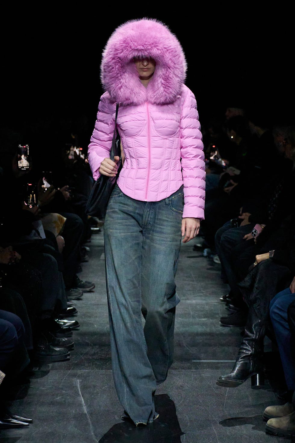 Runway model showcasing a pink puffer jacket and denim jeans