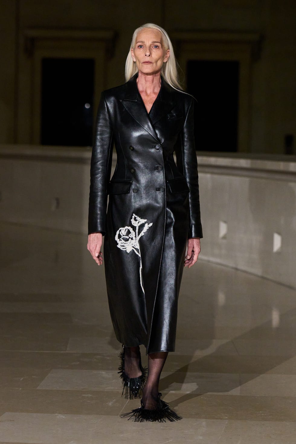 Fashion model showcasing a stylish black leather coat with embroidery