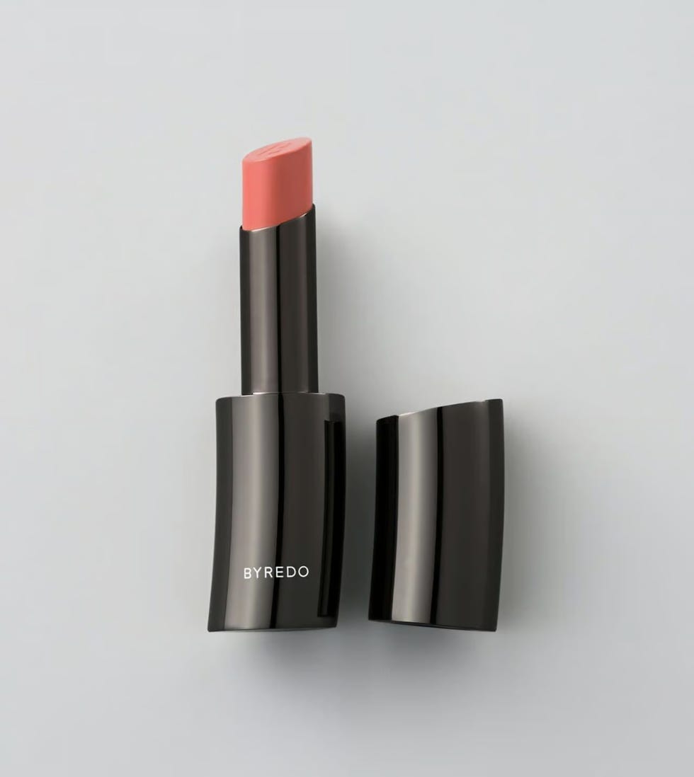 a byredo lipstick tube with its cap removed showcasing a soft pink lipstick bullet
