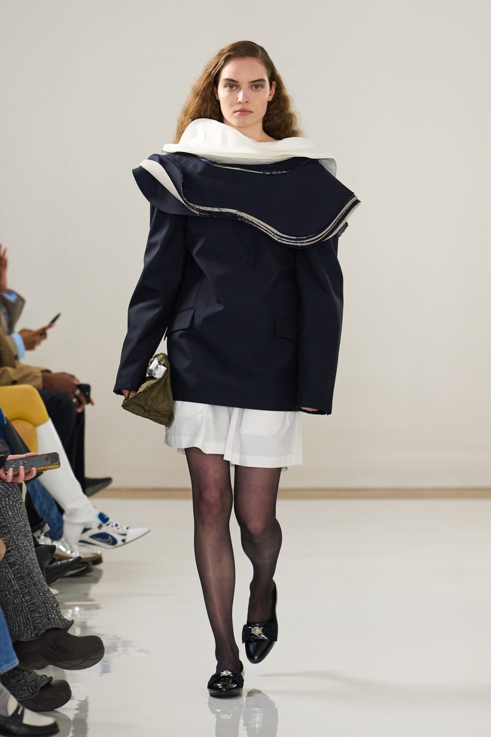 Model wearing a stylish outfit with a large collar and a unique silhouette