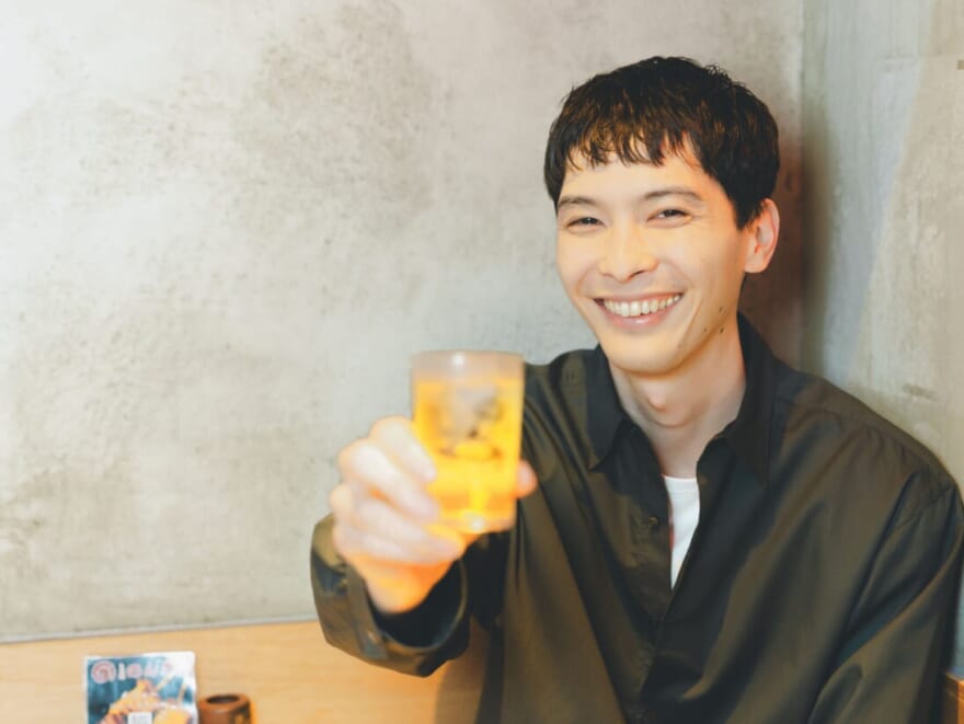 お酒のグラスを持った守屋光治