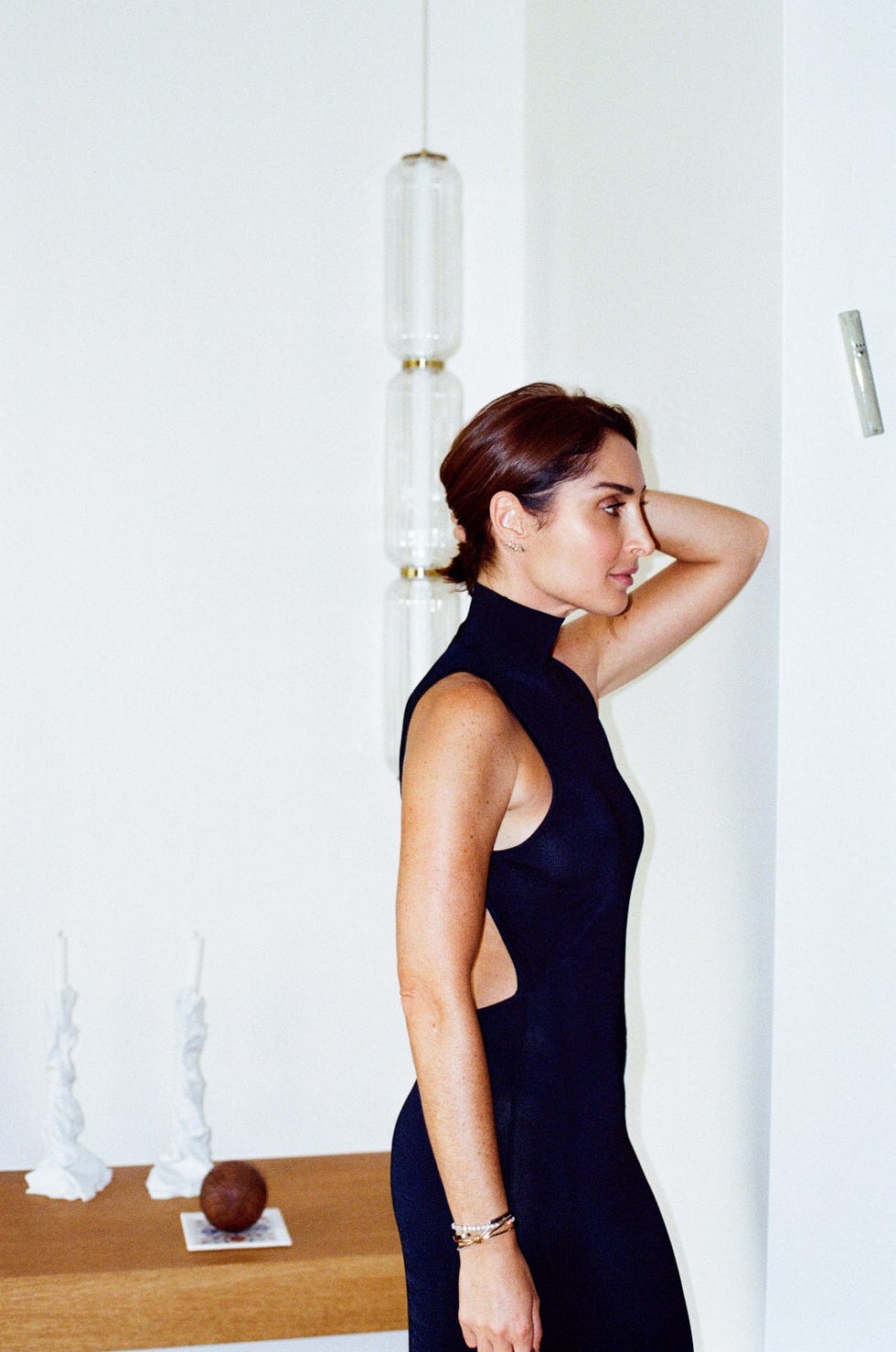 a woman in a fitted black dress standing in a modern interior