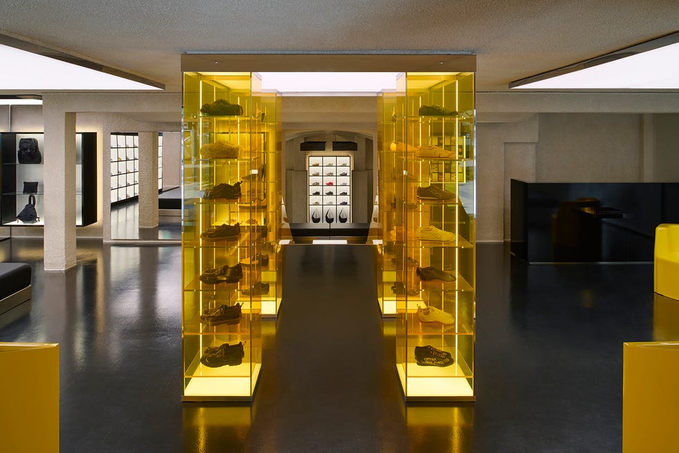 interior of a retail space displaying footwear within yellow illuminated display cases