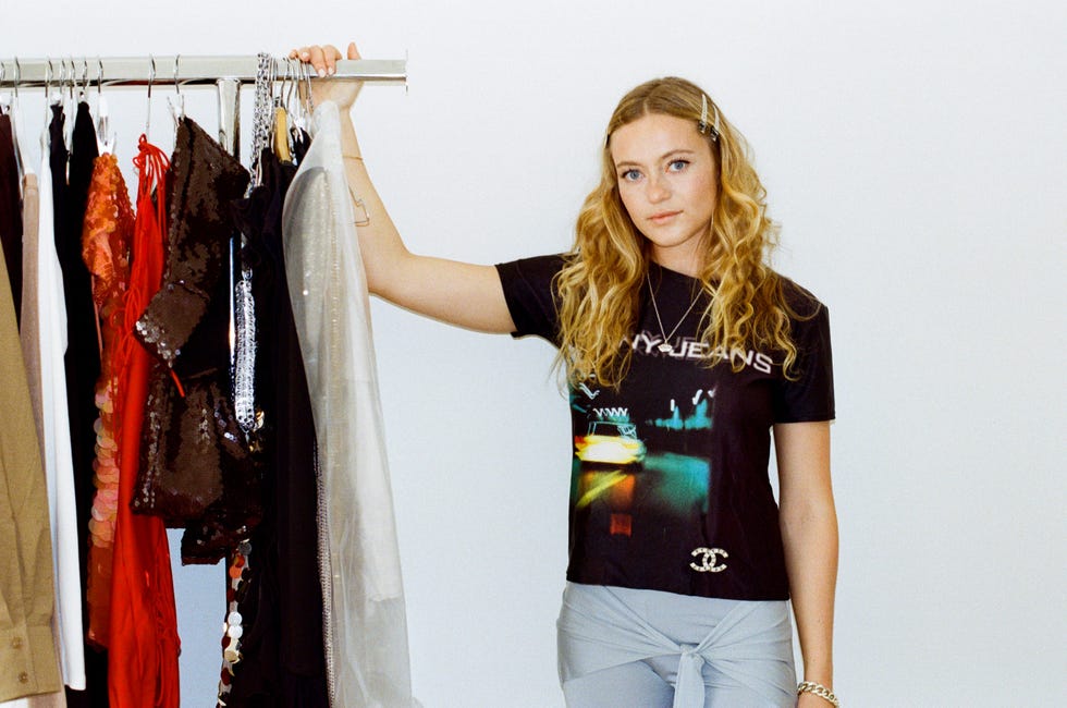 a person holding a clothing rack featuring various garments