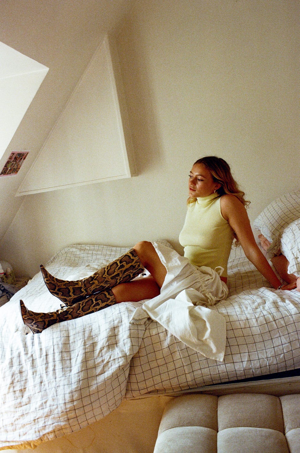 a person sitting on a bed wearing stylish kneehigh boots