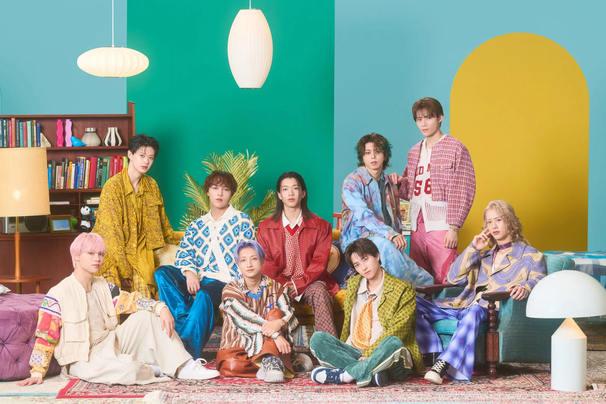 カラフルな衣装を身に着けた、9人組の男性グループの集合写真