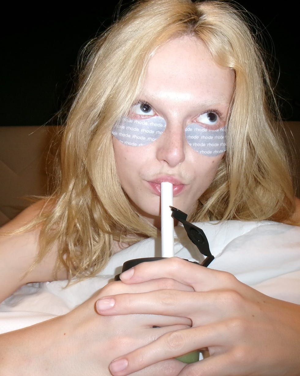 person holding a drink with hands clasped in front