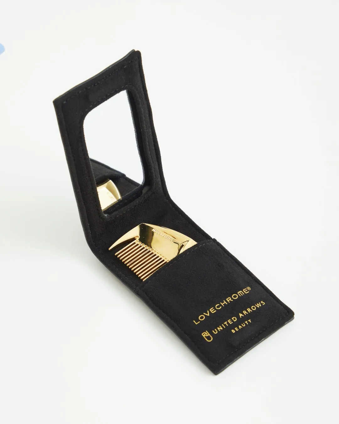 黒いケースに入った金色の櫛と鏡。ケースにはブランド名が記載されています。