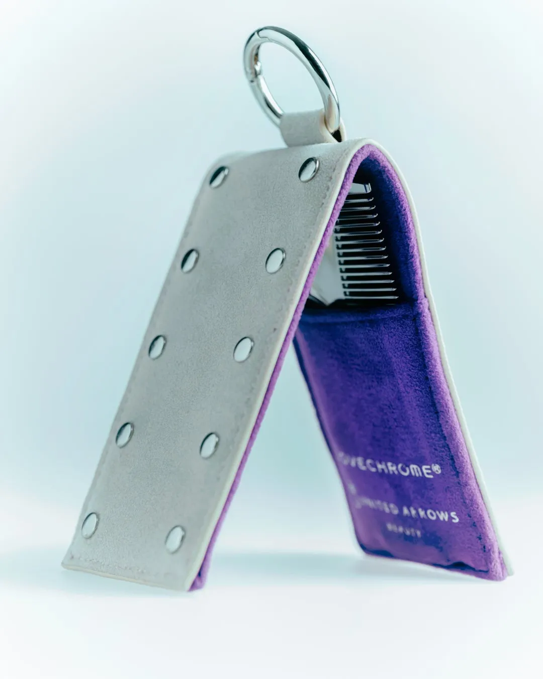 折り畳まれた櫛と、それを収納するケースの写真。ケースは白と紫の組み合わせで、ロゴが印刷されている。