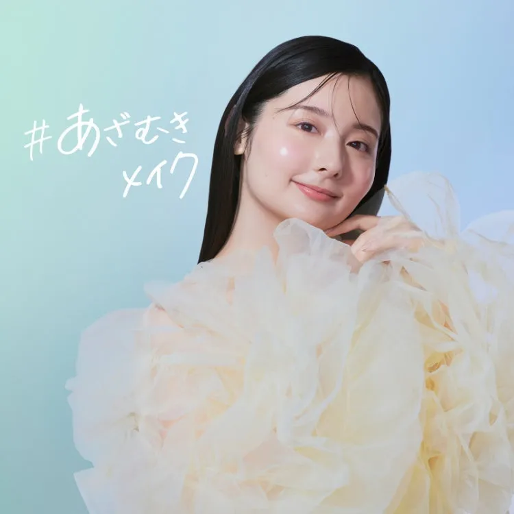 女性のポートレート。女性は明るい肌とメイクをしており、優しい笑顔を浮かべている。背景は水色と白のグラデーション。