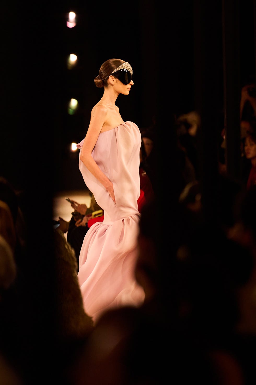 a model walking a runway in a flowing pink gown