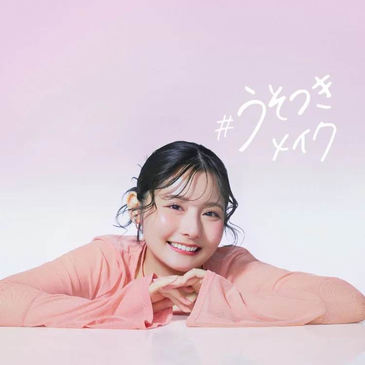 ピンク色の服を着た女性が微笑んでいる写真。背景はピンク色で、写真の上部には「#うそつきメイク」という文字があります。