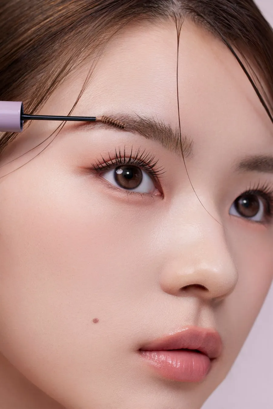 眉毛にブラシをあてている女性の顔のアップ。