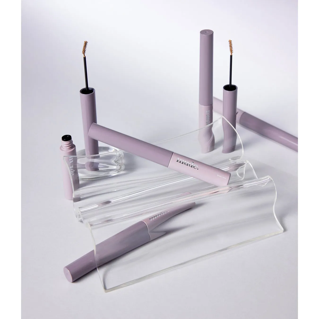 化粧品ブランド「muute.」の眉毛ケア製品の製品写真。製品は、透明なアクリル板の上に置かれ、様々な角度から撮影されている。