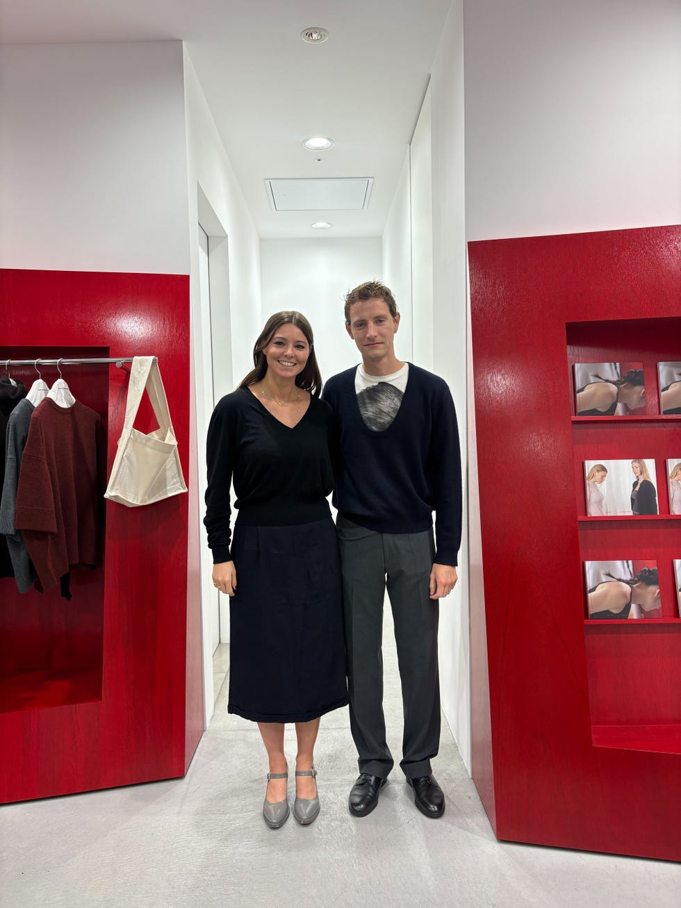 two individuals posing in a modern clothing store interior