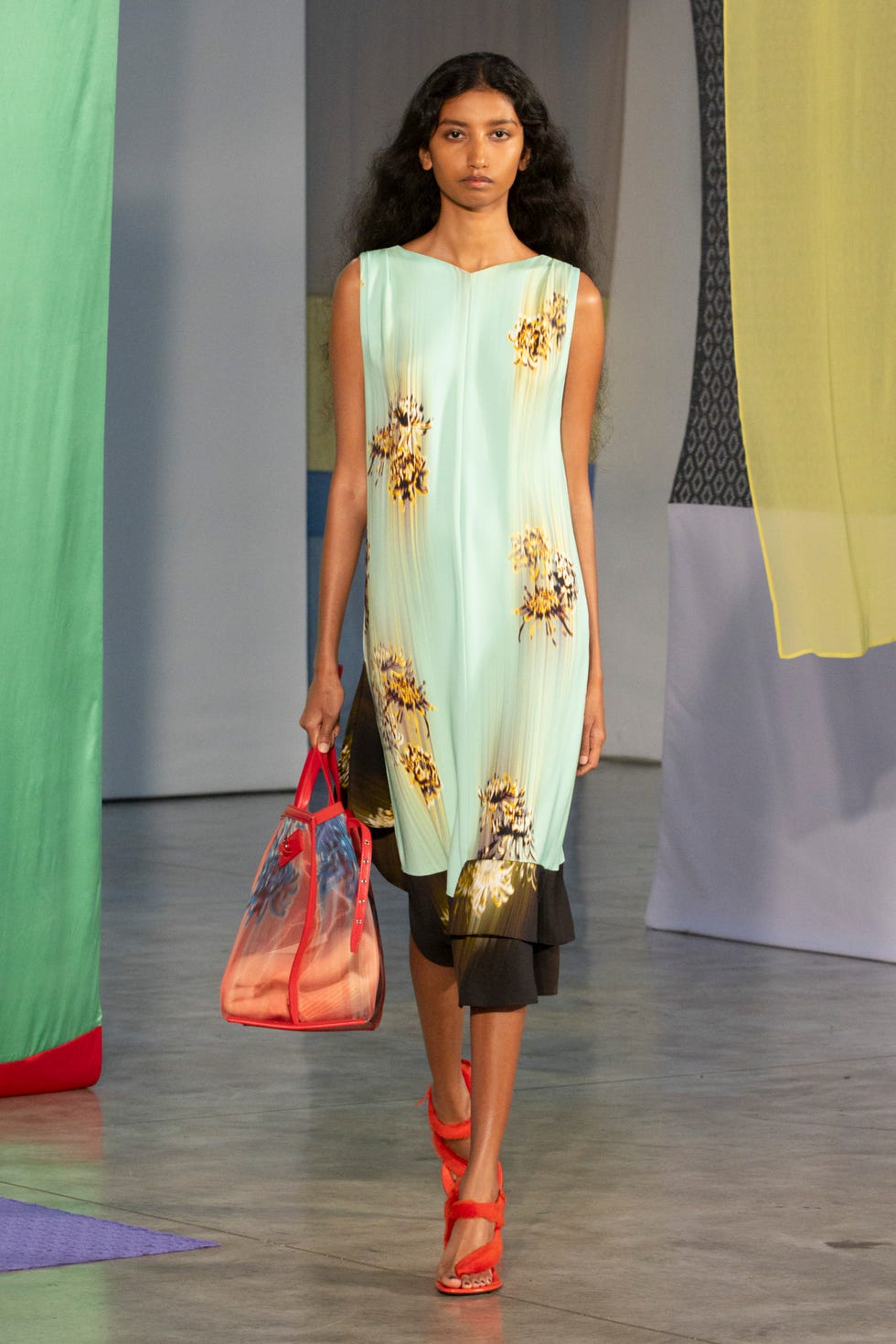 fashion model showcasing a dress and accessories in a runway setting