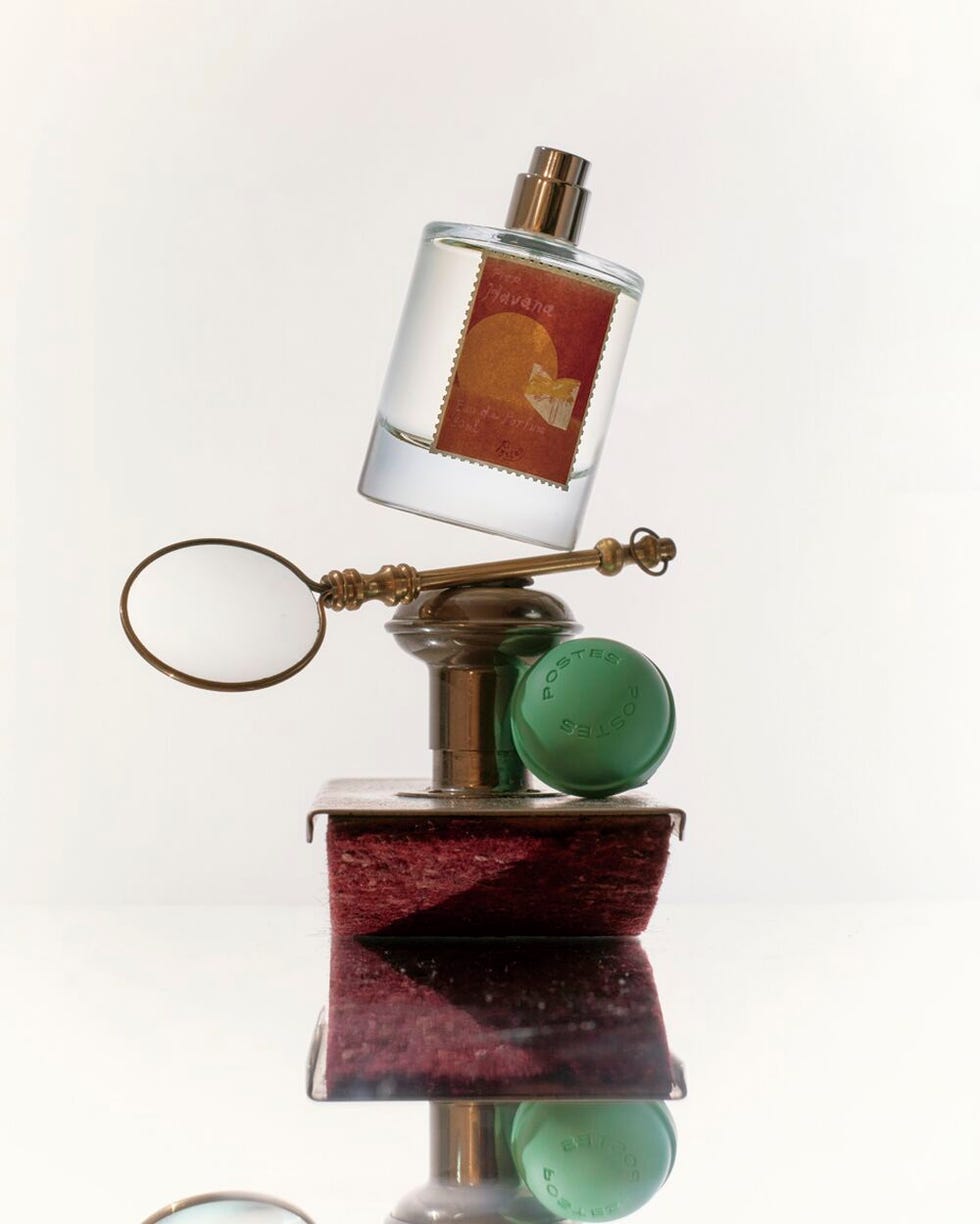 perfume bottle displayed in a balanced arrangement with a vintage magnifying glass and a green cap