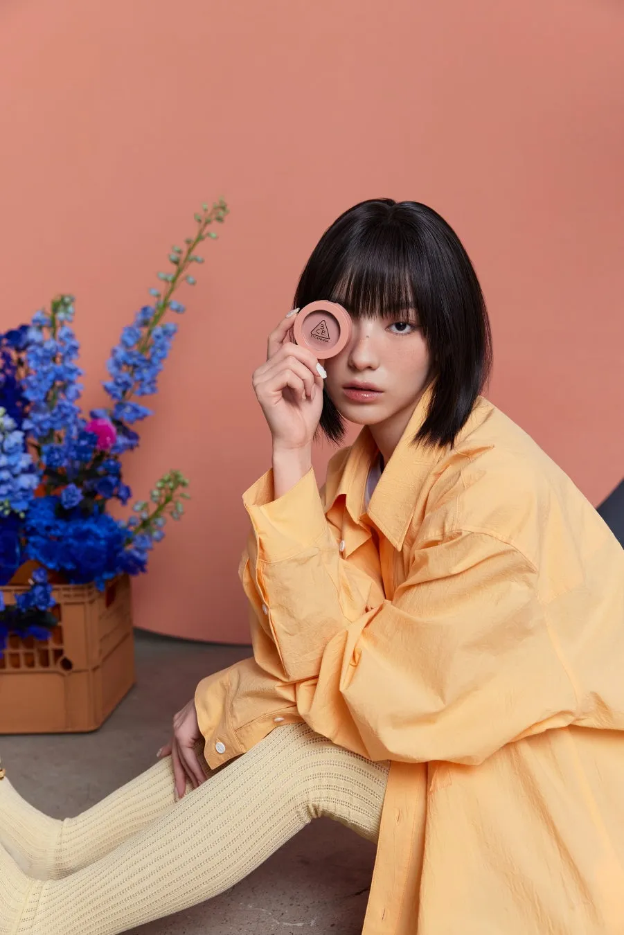 女性が化粧品を持ち、背景に花がある写真