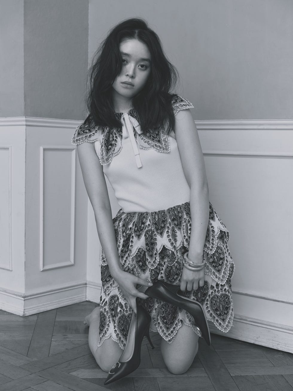 a person kneeling on the floor holding high heels dressed in a decorative outfit