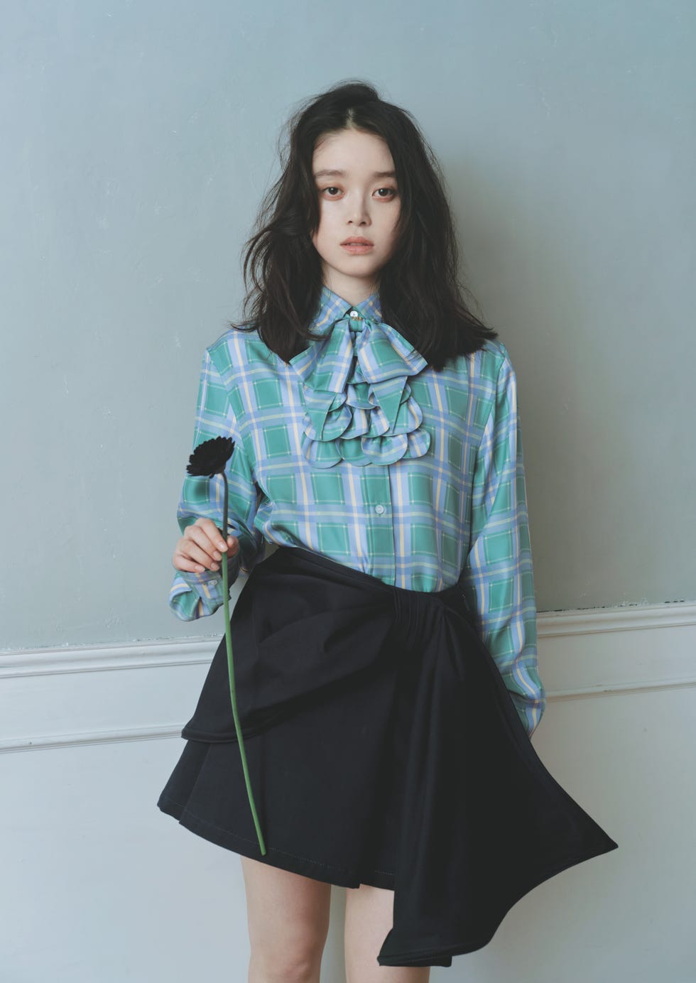 person holding a flower while wearing a trendy outfit