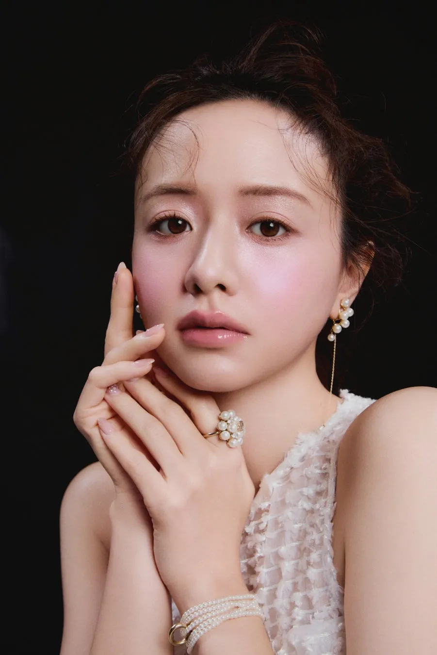 森香澄が魅せる【可憐&クール】な新境地!SNIDEL BEAUTY特設ページ「Soft Glow, Sharp Gaze」本日公開でファン必見! 1 女性のポートレート。白いドレスを着ており、パール風のイヤリング、指輪、ブレスレットを着けている。顔に手を添えている。