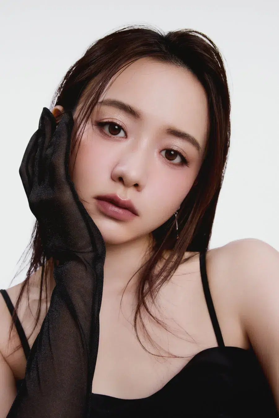 森香澄が魅せる【可憐&クール】な新境地!SNIDEL BEAUTY特設ページ「Soft Glow, Sharp Gaze」本日公開でファン必見! 5 黒い手袋をつけた女性のポートレート。女性はカメラを見ており、白い背景に黒いキャミソールを着ている。