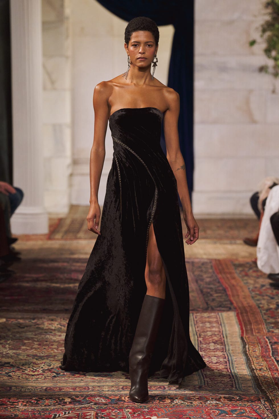 model walking the runway in a black evening gown with a split