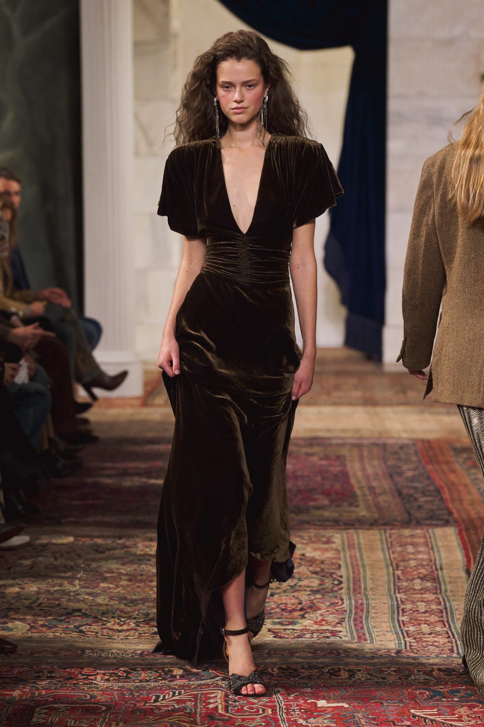fashion model walking down a runway in a dark velvet dress