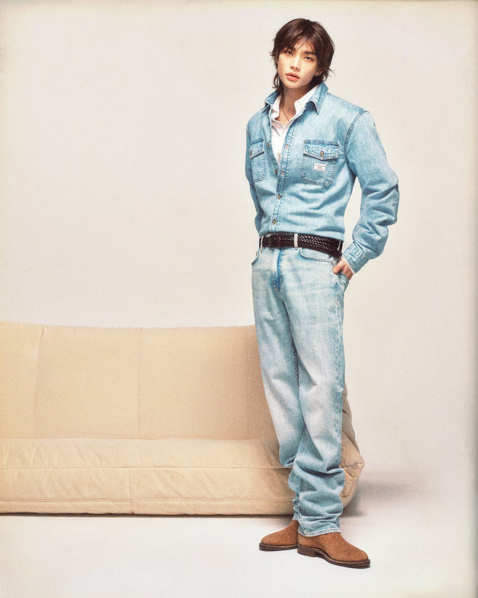 person standing casually next to a couch wearing denim attire