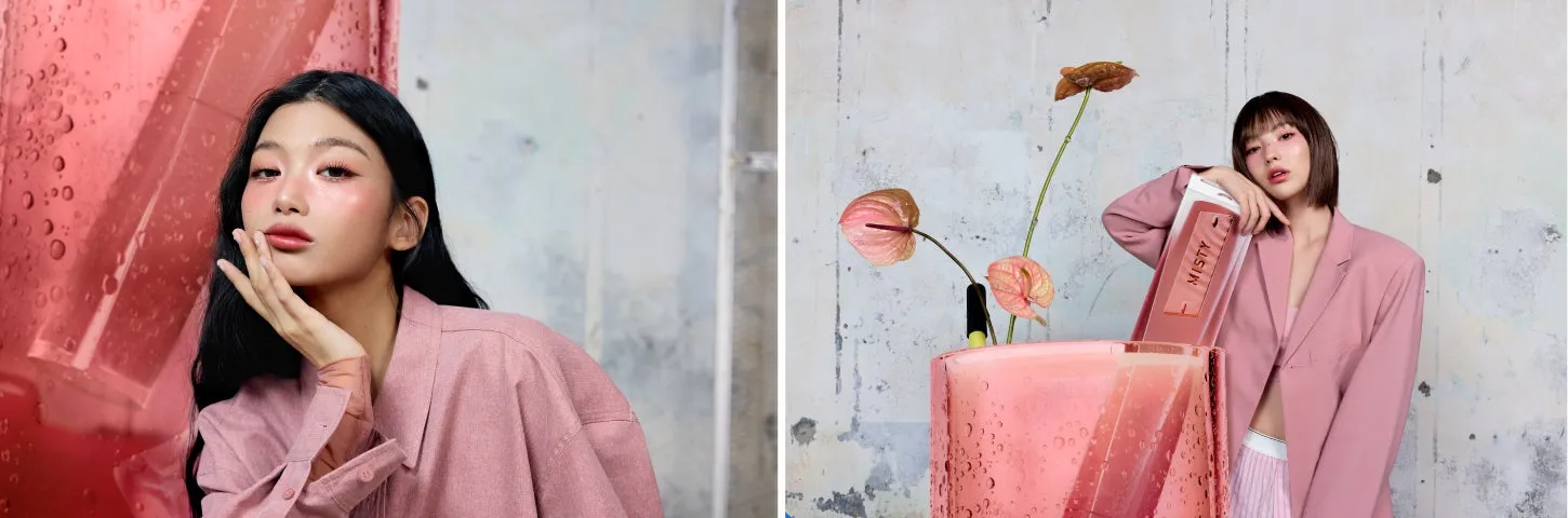 2人の女性が写っている画像です。どちらの女性もピンク色のジャケットを着ており、メイクをしています。片方の女性は赤い背景の前に立っており、もう片方の女性は花と化粧品を持っています。