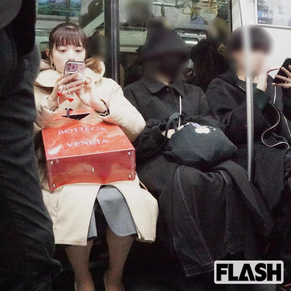 相手男性と離れて電車に座る三谷アナ。高級ブランドのショッピング袋が目立つ