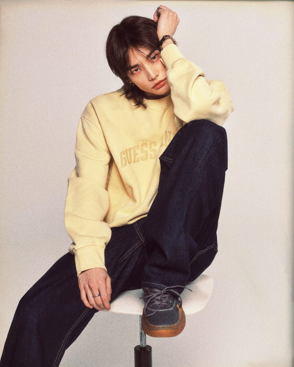 casual fashion model posing on a stool in a studio