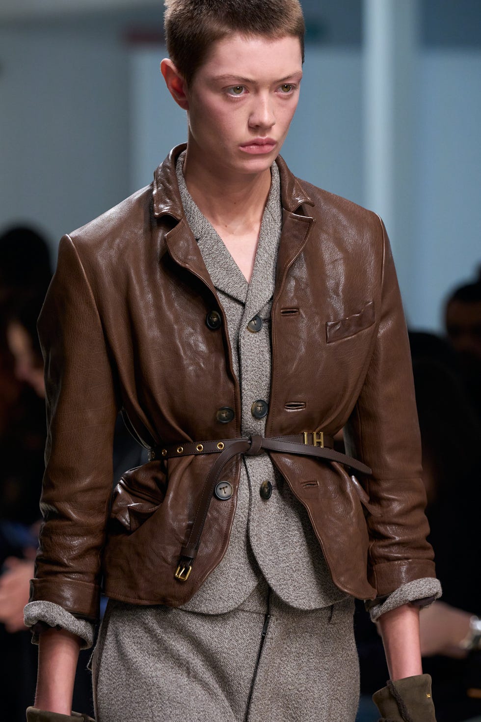 fashion model wearing a stylish outfit with a brown leather jacket and gray ensemble