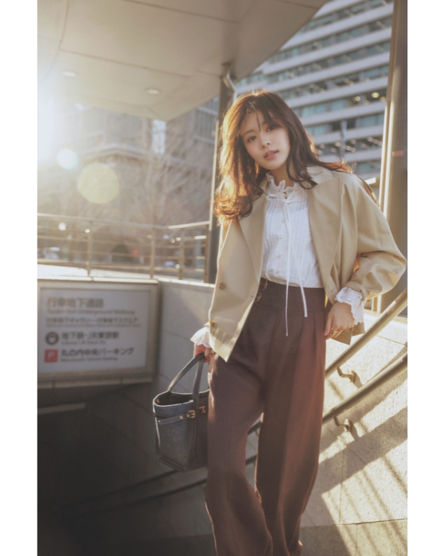 ベージュのショート丈トレンチ×白のフリルブラウス×ブラウンパンツコーデ