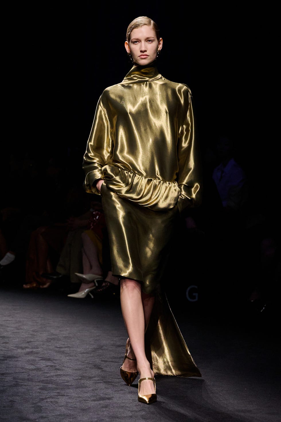 model wearing a shiny golden dress on a runway