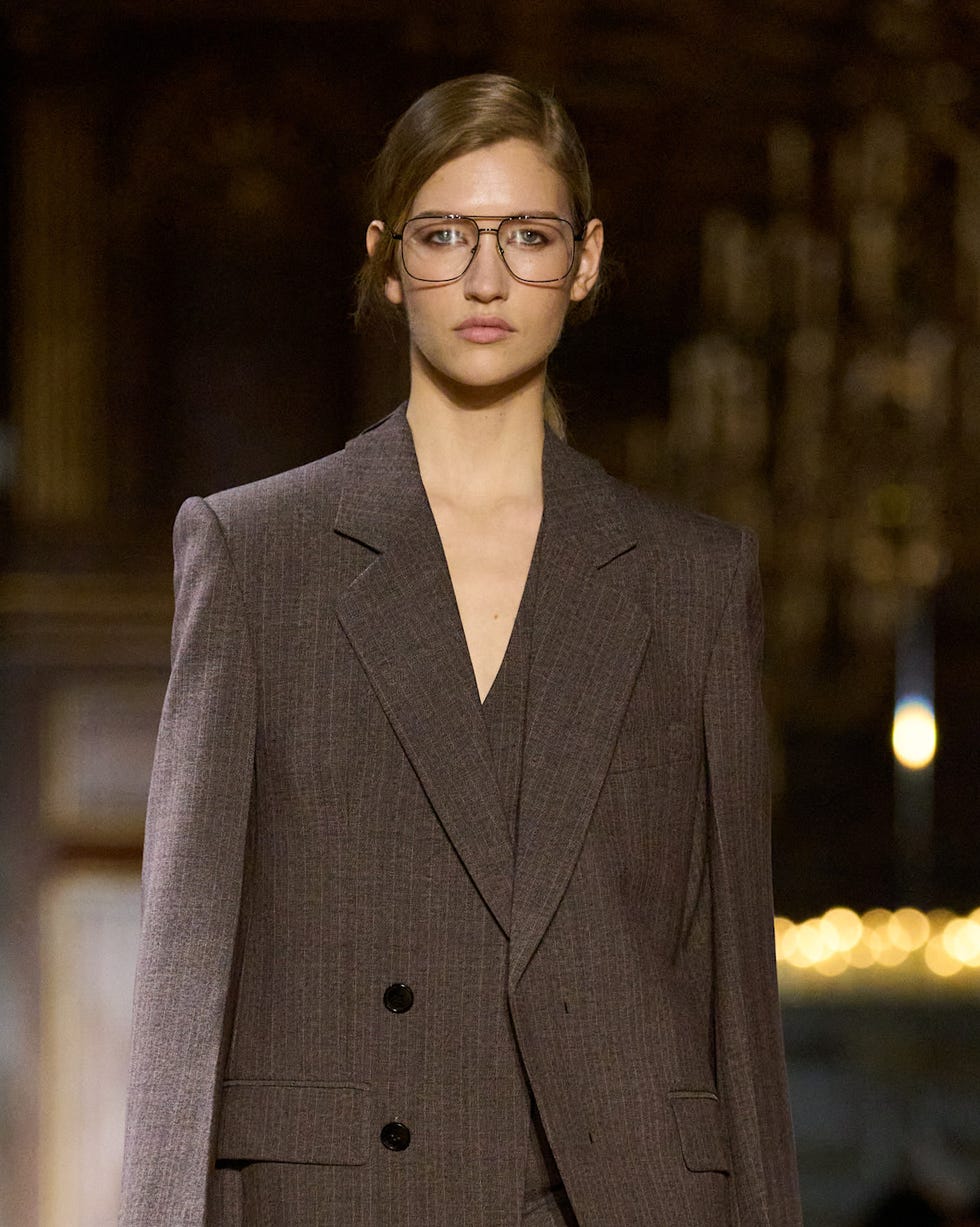 runway model wearing a tailored grey suit with a handbag runway model wearing a tailored grey suit with a handbag