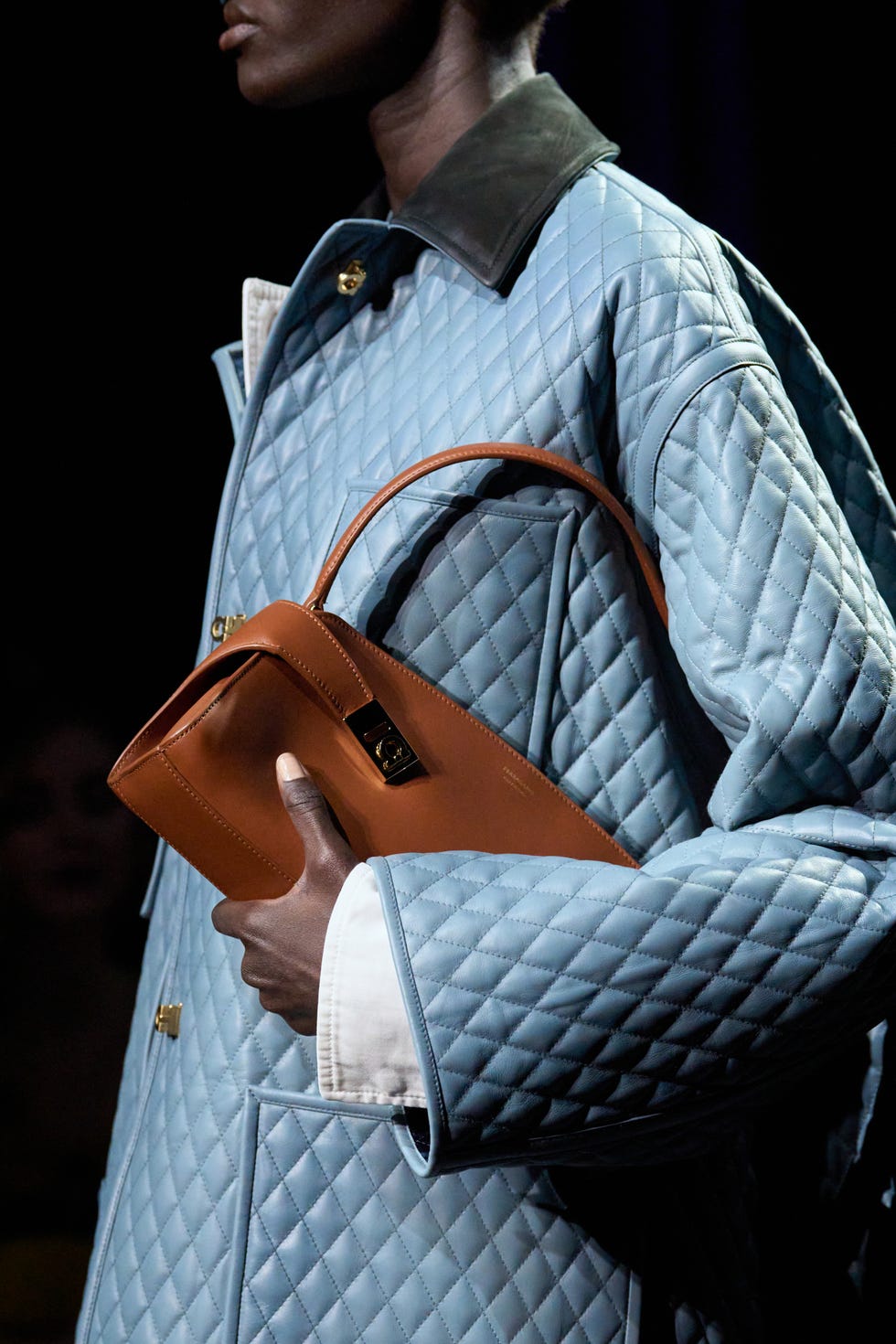 model holding a handbag while wearing a quilted jacket