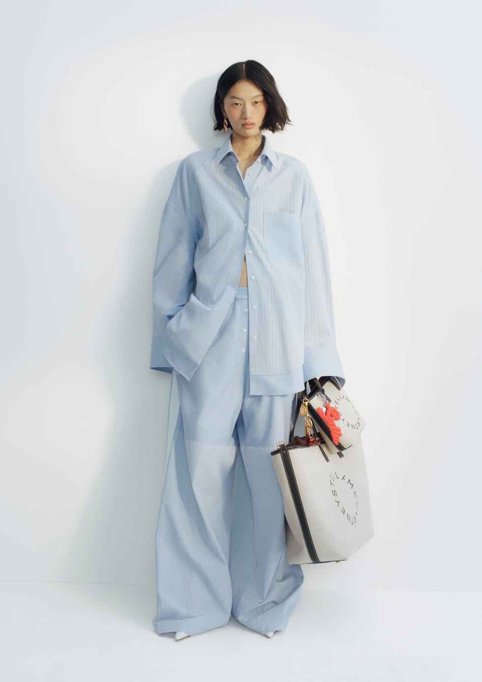 casual outfit featuring a light blue striped shirt and pants complemented by a stylish handbag