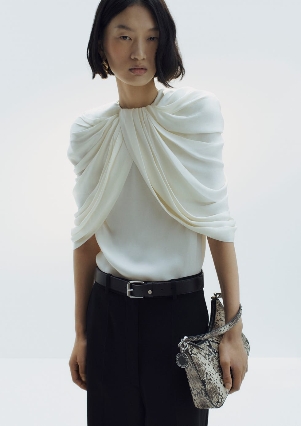 fashionable outfit featuring a draped top and patterned handbag