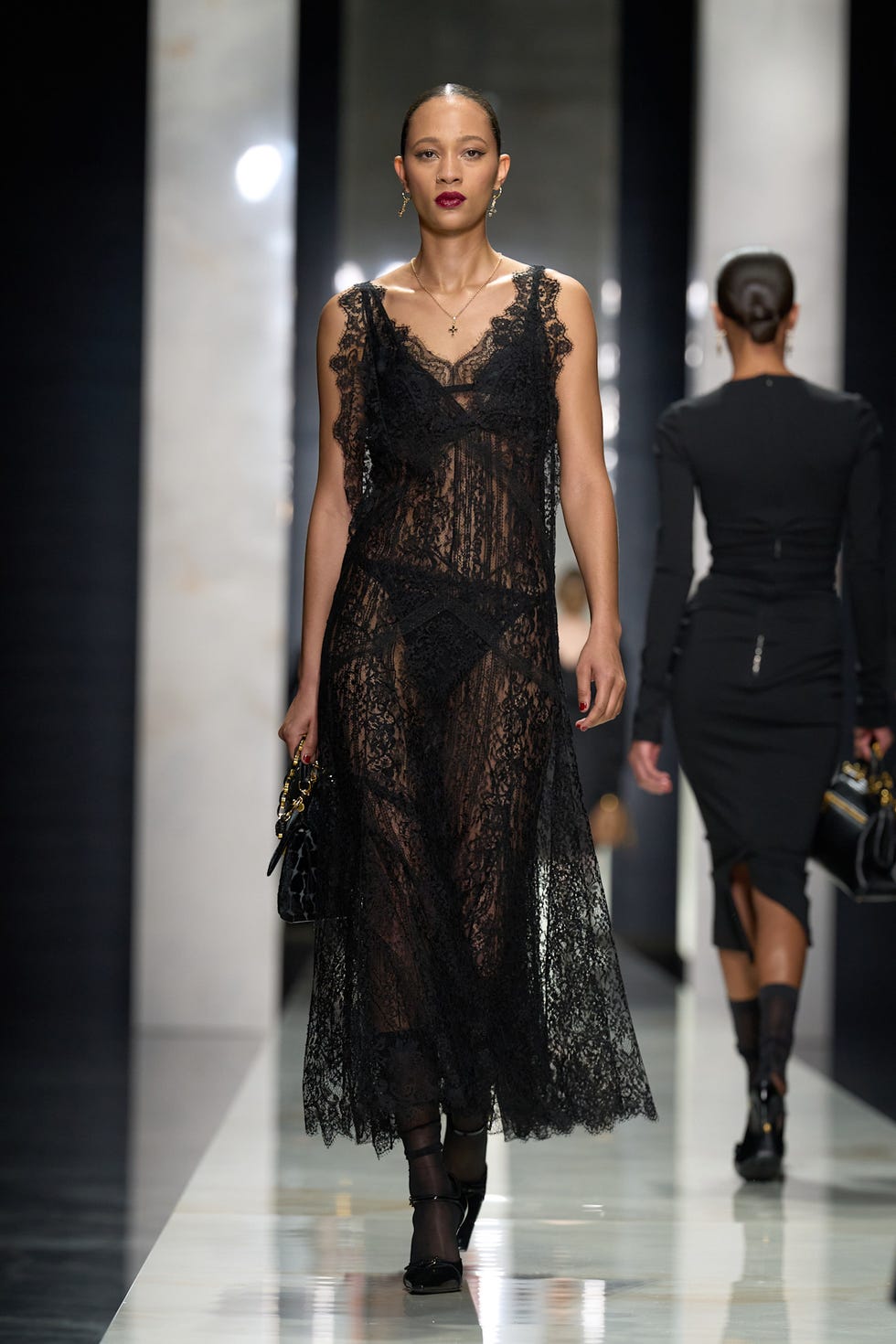 model walking on a runway wearing a black lace dress