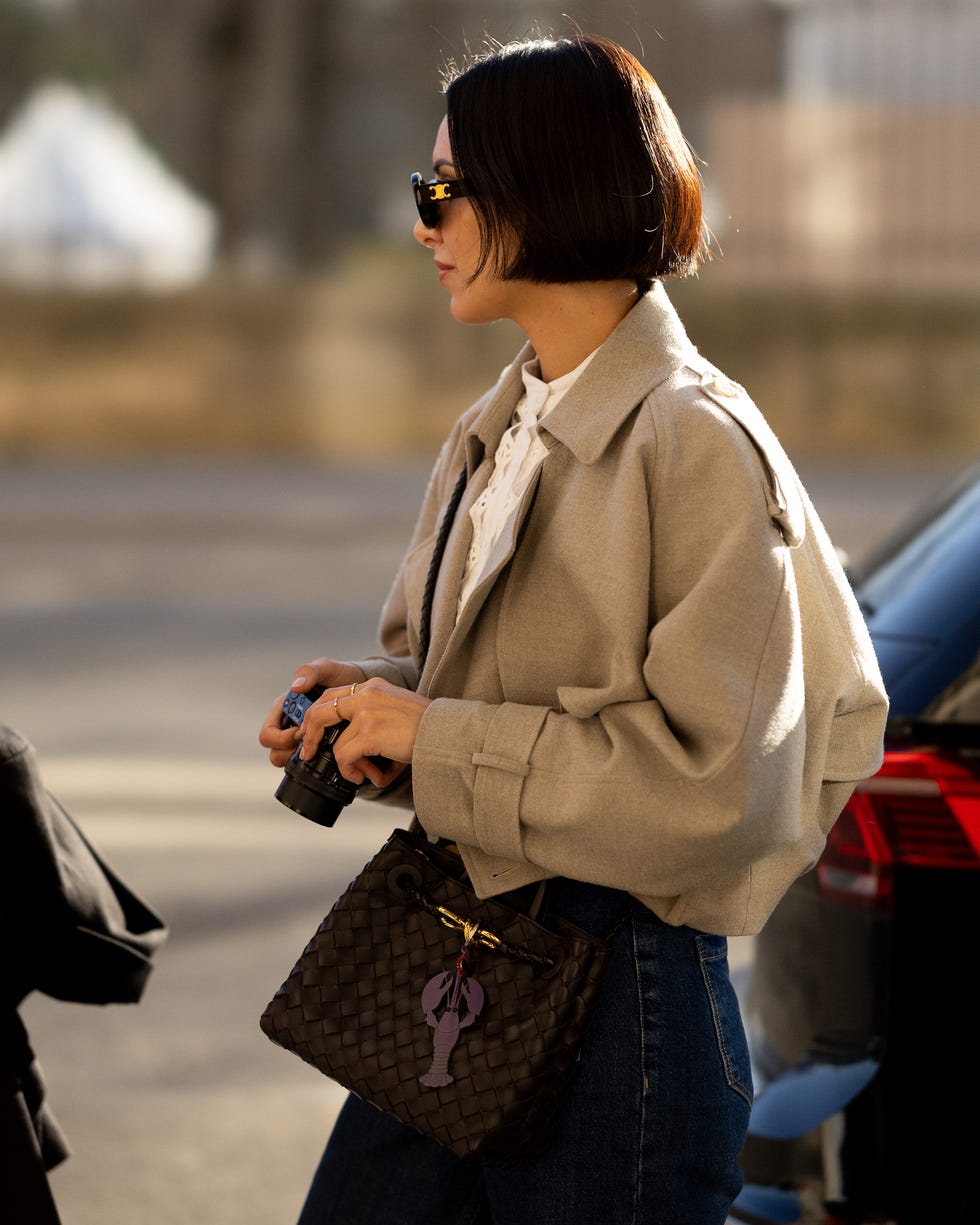 a woman holding a camera while wearing a stylish outfit
